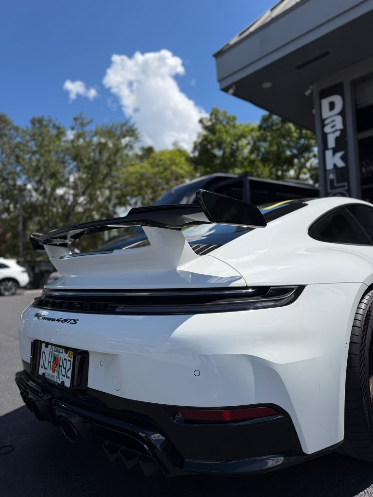 Alerón trasero y carrocería blanca de un Porsche 911 GT3 frente al taller
