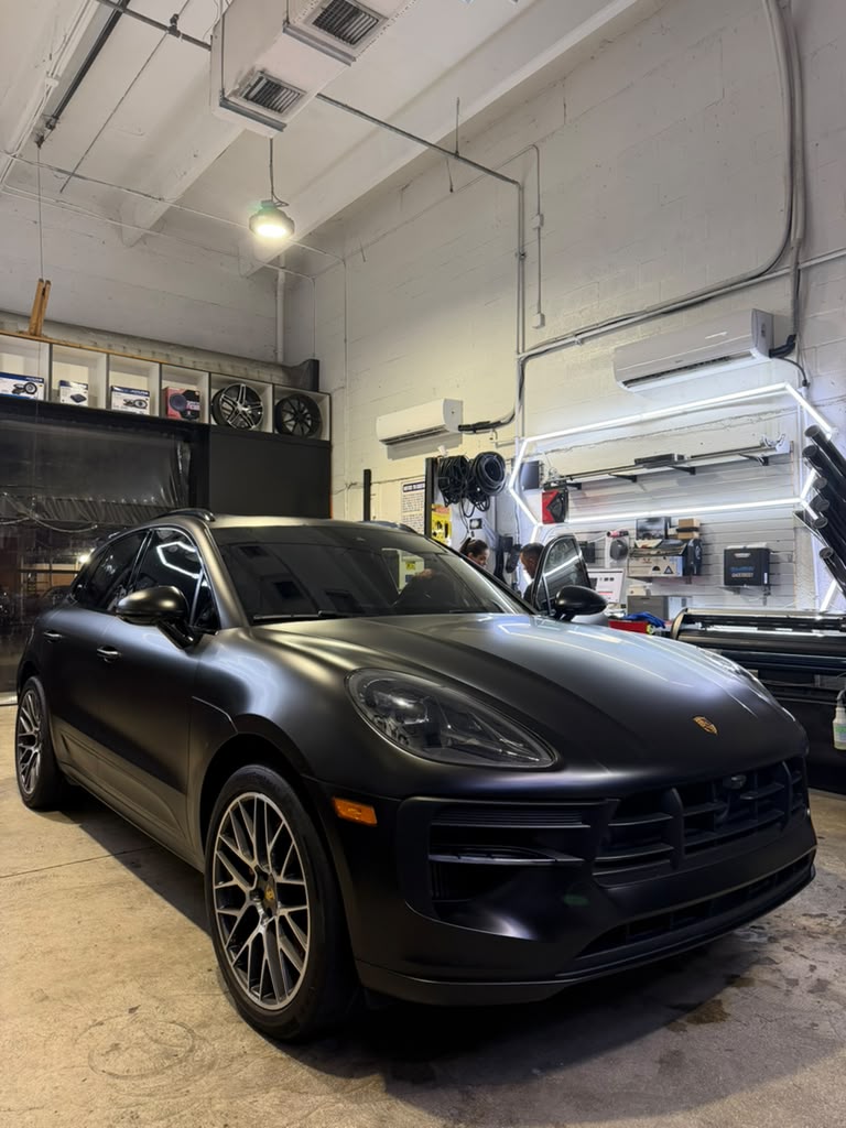 Porsche Macan oscuro mate dentro del taller Dark & Loud en Miami