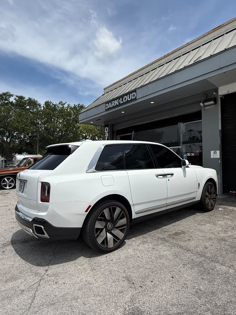 SUV Rolls-Royce blanco con vidrios laterales oscuros frente a Dark & Loud